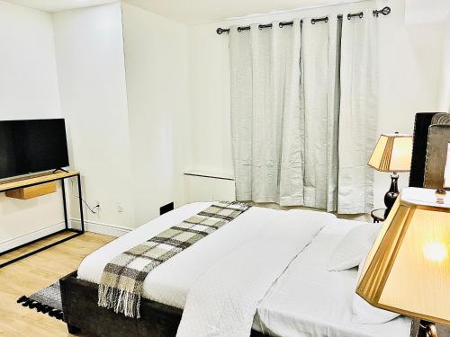 a white bedroom with a bed and a television at LaVida Exclusive Guest House, Free Parking (Rm#2) in London