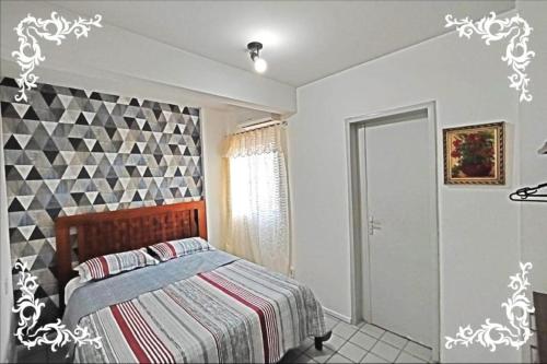 1 dormitorio con cama y pared geométrica en Porto da praia na Jatiuca, en Maceió