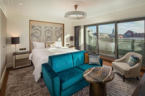 a bedroom with a large bed and a blue couch at Matild Palace, a Luxury Collection Hotel in Budapest