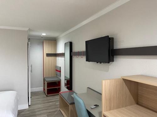 Habitación con cama y TV en la pared. en Roy Inn & Suites -Sacramento Midtown, en Sacramento
