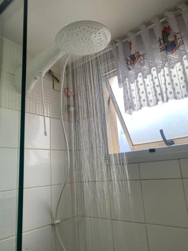 a shower with a shower curtain and a window at Apto com conforto que você precisa. in Goiânia
