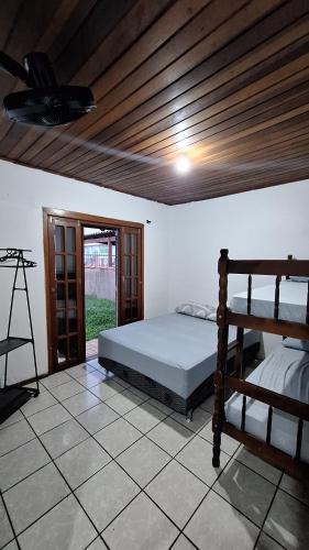 1 dormitorio con cama y techo de madera en Casa com quintal próxima de Torres, en Passo de Torres