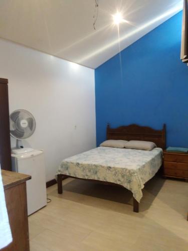a bedroom with a bed with a blue wall at Suíte paraty in Paraty
