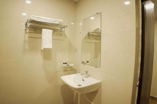 a white bathroom with a sink and a mirror at Hotel Grand Residency in Jamshedpur