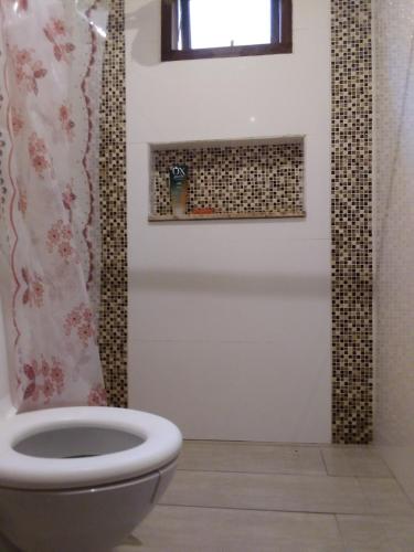 a bathroom with a toilet and a window at Suíte paraty in Paraty