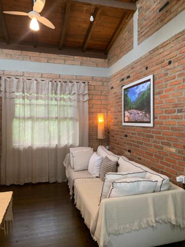 ein Wohnzimmer mit 2 Betten und einer Ziegelwand in der Unterkunft Casa ecológica na Montanha in Praia Grande