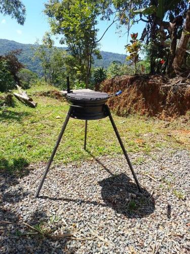a barbecue grill on a stand in the grass at Finca Makambu in Platanillo
