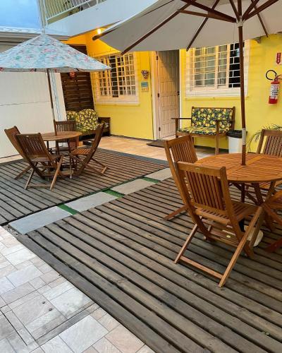 a patio with a wooden table and chairs and umbrellas at Pousada Ilha dos Corais in Palhoça