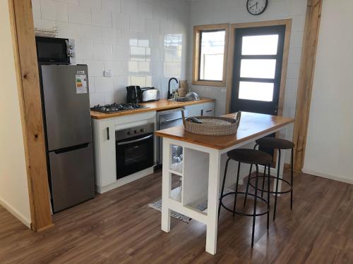 a kitchen with a refrigerator and a table with stools at Casa Bulnes in Constitución