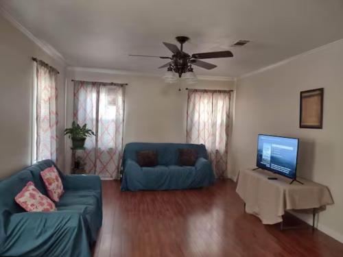uma sala de estar com um sofá azul e uma televisão em Simple Private Bedroom # 2 em Alexandria