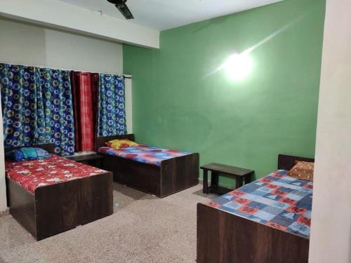 a room with three beds and a table in it at sri rama krishna pg in Pune