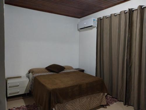 Praia inglesese في فلوريانوبوليس: غرفة نوم صغيرة بسرير وستارة