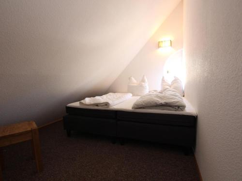 uma pequena cama com lençóis brancos e almofadas num quarto em Studio in Buchholz on Lake Müritz em Buchholz