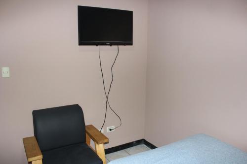 um quarto com uma cadeira e uma televisão na parede em Hotel Dorado em San José