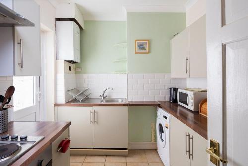 a kitchen with white cabinets and a sink at Welcoming Flat By Kasar Stays in Gillingham