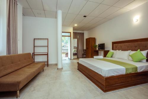 a bedroom with a large bed and a couch at Villa Windfall Unawatuna in Unawatuna