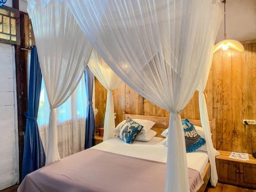 um quarto com uma cama de dossel branca com cortinas azuis em Krui Surfing em Wainapal