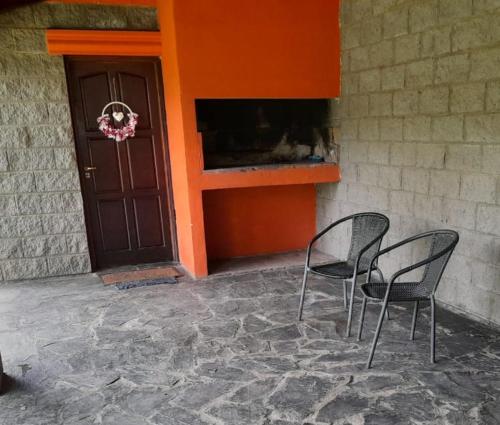 duas cadeiras sentadas em frente a um edifício com uma porta em La Casita del Río em Villa Ciudad Parque