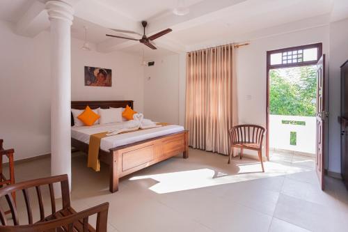 a bedroom with a bed and a chair and a window at Villa Windfall Unawatuna in Unawatuna