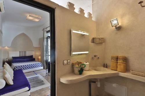 Riad Modern Bed & Breakfast في مراكش: حمام مع حوض ومرآة وسرير