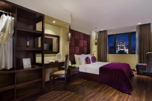 a hotel room with a bed and a desk and a window at Ambassador Hanoi Hotel & Spa in Hanoi