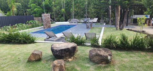 un patio trasero con piscina y rocas en el césped en Loma linda Village, en Pedro García