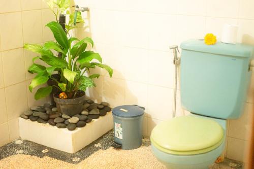 a bathroom with a blue toilet and a potted plant at I Gusti Nyoman Oka Homestay in Ubud