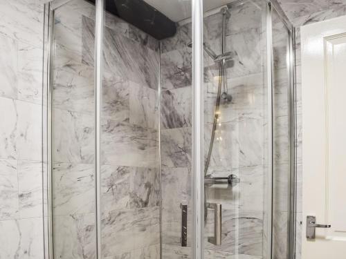 a shower with a glass door in a bathroom at Beck Cottage in Millom