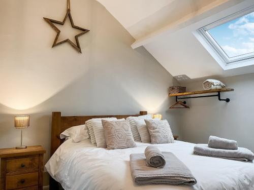 The Old Hayloft-uk39431 في درونفيلد: غرفة نوم بسرير ومخدات بيضاء ونجمة على الحائط