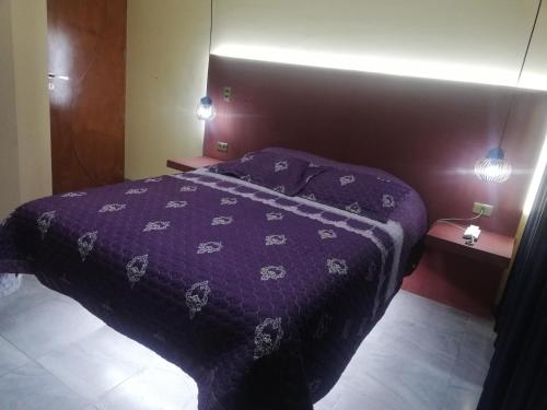 a bed with a purple comforter in a bedroom at Hostal sublime in Cochabamba