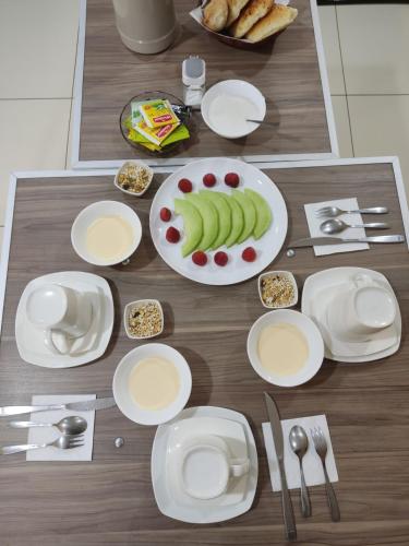 uma mesa com pratos brancos de comida e fruta em Hostal sublime em Cochabamba