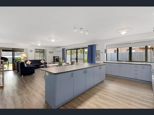a large kitchen and living room with a large island at Cheerful 3 Bedroom House with cozy wood fire. in Inverloch