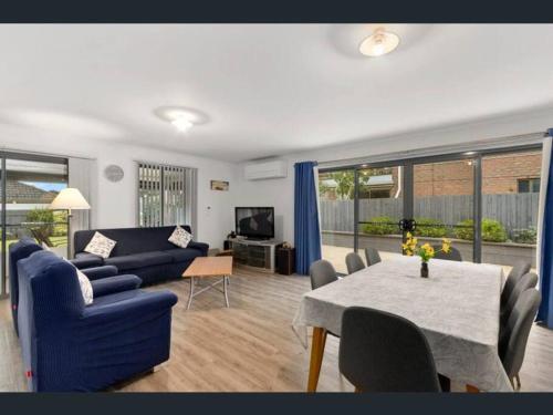a living room with a blue couch and a table at Cheerful 3 Bedroom House with cozy wood fire. in Inverloch