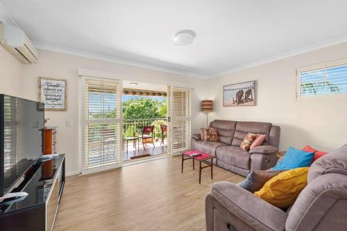 a living room with a couch and a television at Bright & Breezy ~ 2 Bed/2 Bath /1 Car/ Views! in Brisbane