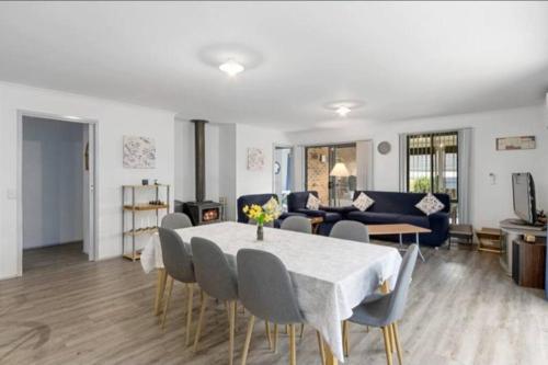 a living room with a table and chairs and a couch at Cheerful 3 Bedroom House with cozy wood fire. in Inverloch