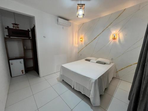 a white bedroom with a bed and a wall at Maceió Kite House in Camocim