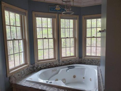 a large bath tub in a bathroom with windows at LakePath Beach House - XL hot tub, walk to beach in Coloma