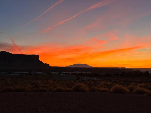 a sunset in the desert with a mountain in the background at Canyon Dweller Luxury home with Mesa views in Big Water