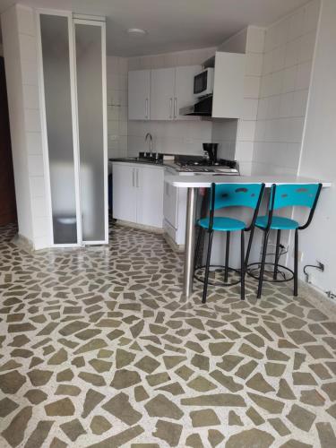 an empty kitchen with blue chairs and a counter at Bonito apartamento con excelente ubicación in Manizales