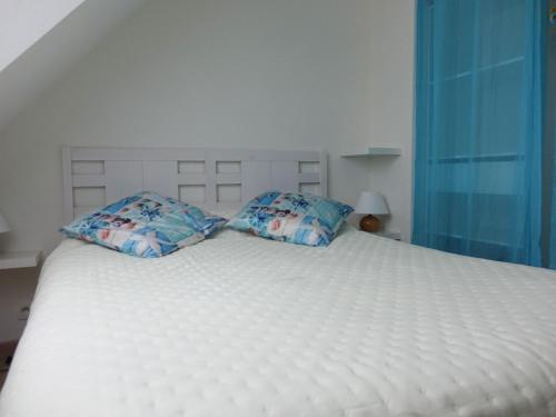 Una cama blanca con dos almohadas encima. en Maison Sarzeau, 3 pièces, 6 personnes - FR-1-639-102, en Sarzeau