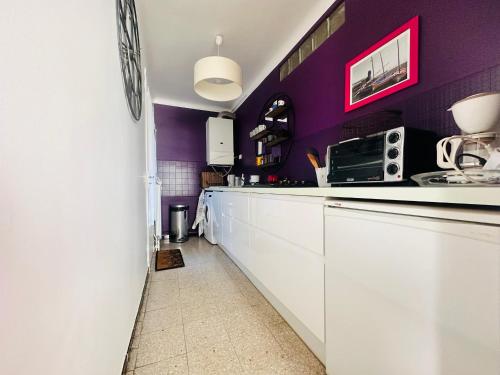 une cuisine avec des armoires blanches et des murs violets dans l'établissement Appartement T3 à Collioure, 200m de la plage, résidence calme avec parking et balcons - FR-1-309-417, à Collioure
