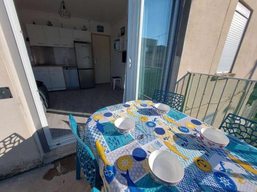 une table avec des assiettes et des bols dessus sur un balcon dans l'établissement Appartement T2 à Marseillan Plage : terrasse, jardin, parking, proche plage et commerces - FR-1-326-796, à Marseillan