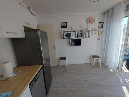 Il comprend une cuisine équipée d'un réfrigérateur et de 2 chaises. dans l'établissement Appartement T2 à Marseillan Plage : terrasse, jardin, parking, proche plage et commerces - FR-1-326-796, à Marseillan