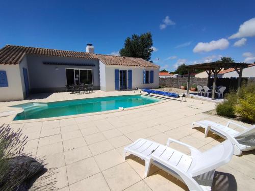 une piscine avec deux chaises blanches et une maison dans l'établissement Maison avec Piscine Privée, Jardin Clos et Parking proche Plage et Forêt à Saint Jean de Monts - FR-1-323-468, à Saint-Jean-de-Monts