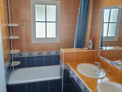 une salle de bain avec un lavabo, une baignoire et un miroir dans l'établissement Maison avec Piscine Privée, Jardin Clos et Parking proche Plage et Forêt à Saint Jean de Monts - FR-1-323-468, à Saint-Jean-de-Monts
