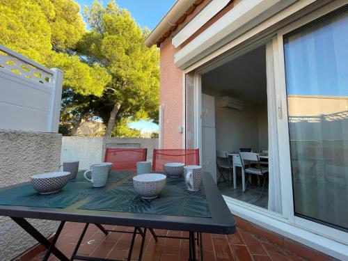 - une table avec des bols et des tasses sur la terrasse dans l'établissement Appartement Climatisé à Sète – Terrasse, WIFI, Parking Privé, à 500m de la Plage - FR-1-338-546, à Sète