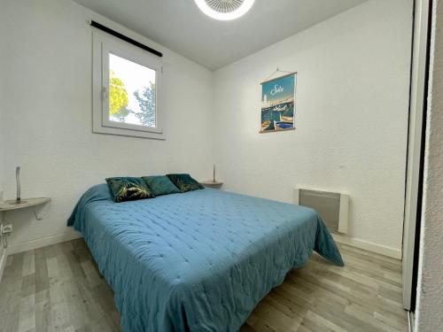 une chambre avec un lit avec une couette bleue et une fenêtre dans l'établissement Appartement Climatisé à Sète – Terrasse, WIFI, Parking Privé, à 500m de la Plage - FR-1-338-546, à Sète