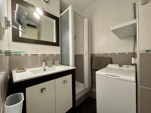 une salle de bain blanche avec un lavabo et un miroir dans l'établissement Appartement Climatisé à Sète – Terrasse, WIFI, Parking Privé, à 500m de la Plage - FR-1-338-546, à Sète