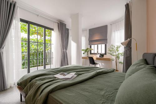 - une chambre avec un lit vert et une fenêtre dans l'établissement M Village Hoàng Văn Thụ, à Hô-Chi-Minh-Ville