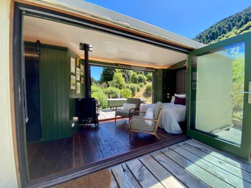 a master bedroom with a deck with a bed and a large window at The Box Car with Outdoor Private Bath in Closeburn